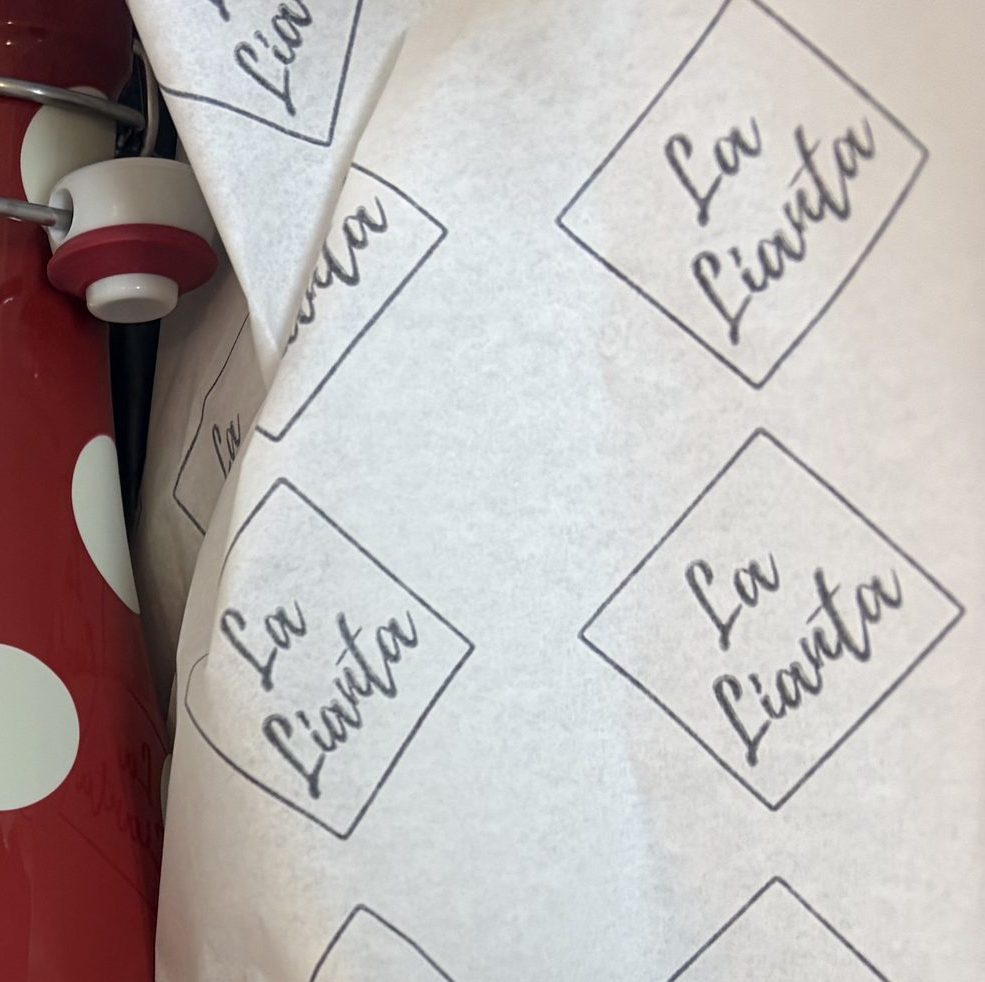 Papel de seda con el sello de La Lianta envolviendo el contenido de una caja